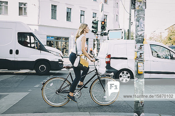 Junge Geschäftsfrau in voller Länge mit dem Fahrrad auf der Straße in der Stadt