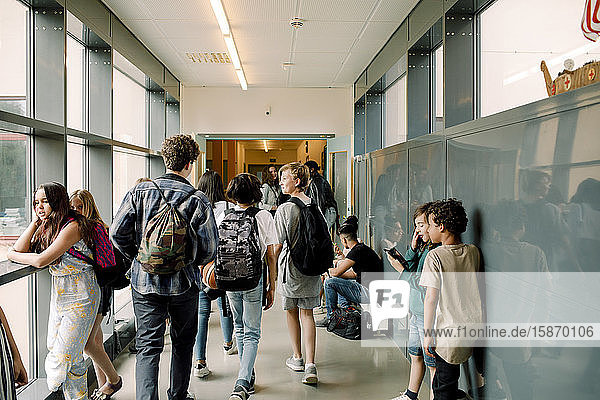 Rear view of students walking in school corridor
