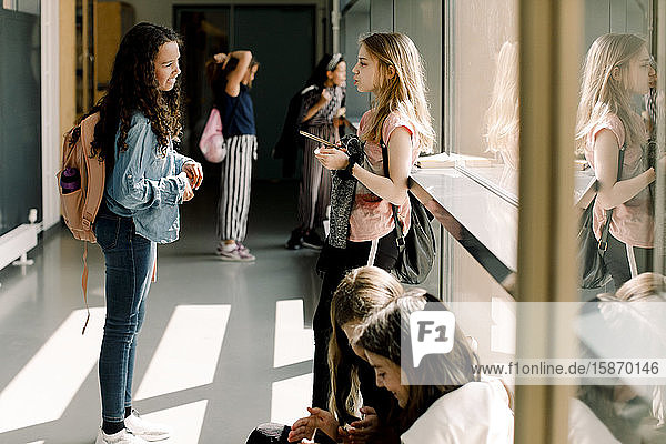 Female students communicating in school corridor during lunch break