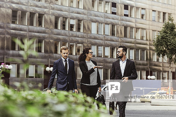 Unternehmerin bespricht Geschäftsstrategie mit männlichen Kollegen beim Spaziergang im Freien