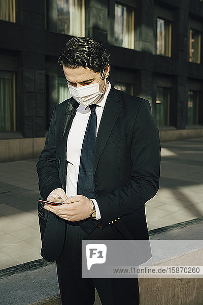 Businessman with face mask using smartphone