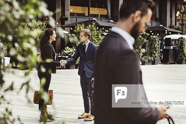 Male and female entrepreneurs shaking hands while standing outdoors