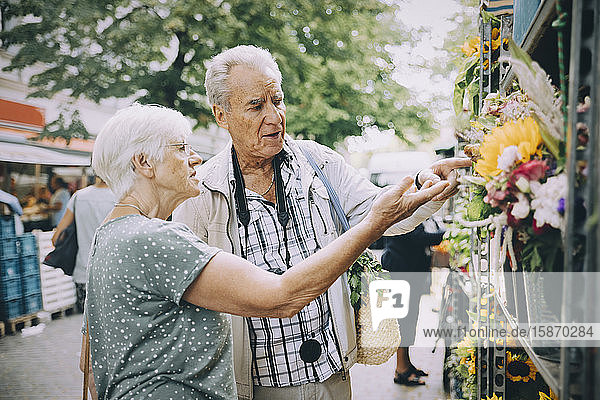 Retired couple discussing while shopping for flowers at market in city
