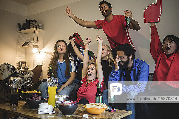 Multiethnische Freunde schauen Sport  während sie zu Hause auf dem Sofa sitzen