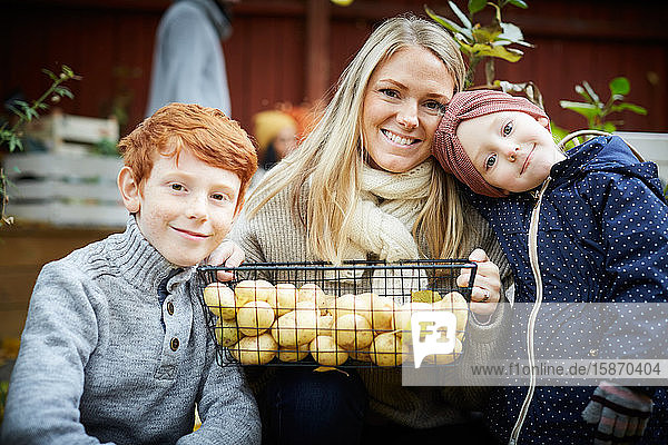 Porträt einer Mutter mit Kartoffelkorb von Kindern im Hof sitzend