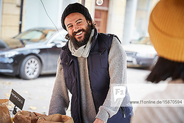 Lächelnder Mann schaut weiblichen Verkäufer an  während er am Marktstand steht