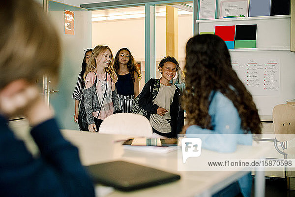 Lächelnde männliche und weibliche Schüler beim Betreten des Klassenzimmers