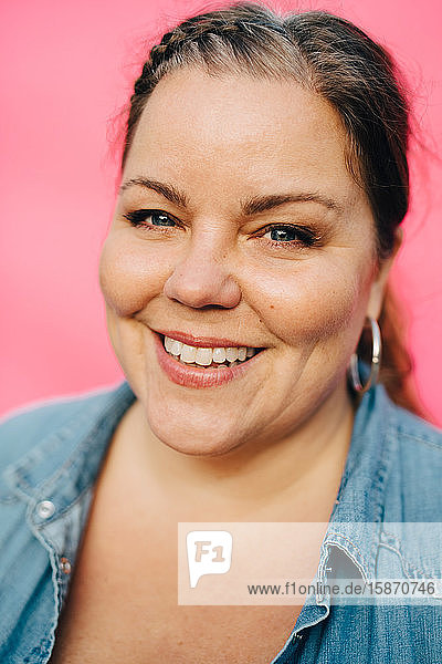 Porträt einer lächelnden reifen Frau vor rosa Hintergrund