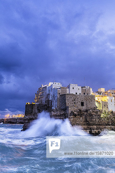 Waves crash on the cliff during a winter storm at dusk Polignano a Mare Apulia Italy Europe