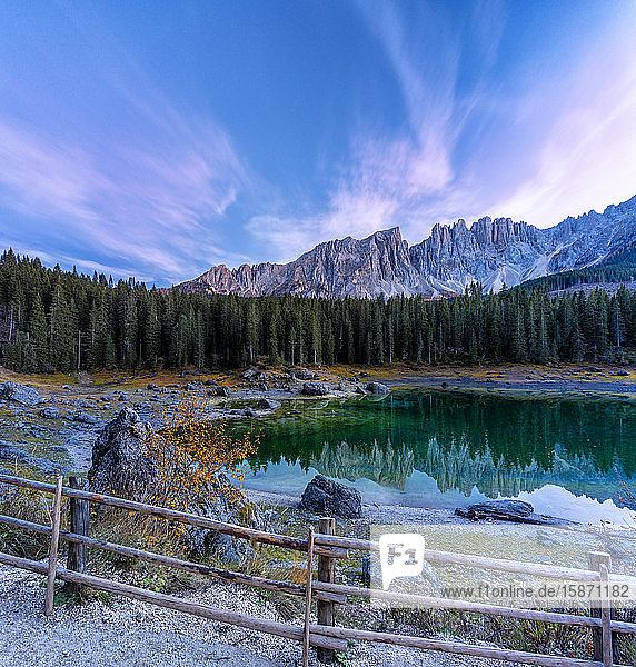 Dramatic sky at sunset over Carezza Lake and Latemar peaks in autumn Dolomites South Tyrol Italy Europe