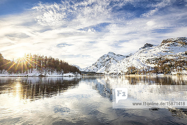 The sun illuminates the icy surfaces of Lake Sils Engadine Valley Graubunden Swiss Alps Switzerland Europe