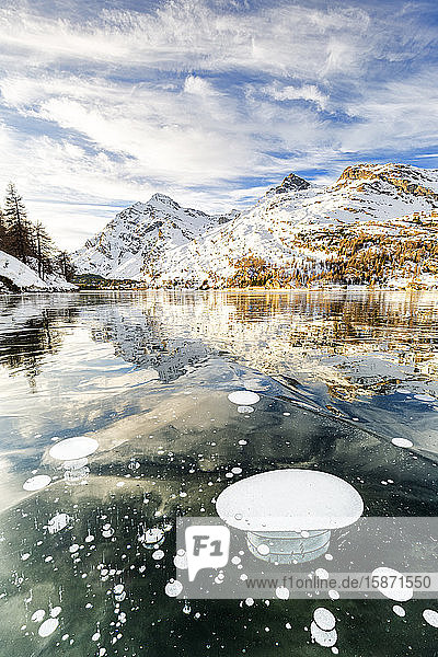 Methane bubbles in the icy surface of Silsersee with snowy peak Lake Sils Engadine Valley Graubunden Swiss Alps Switzerland Europe