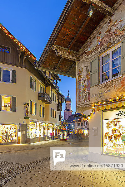 Blick auf die Pfarrkirche St. Martin und die Geschäfte der Stadt in der Abenddämmerung  Garmisch-Partenkirchen  Bayern  Deutschland  Europa