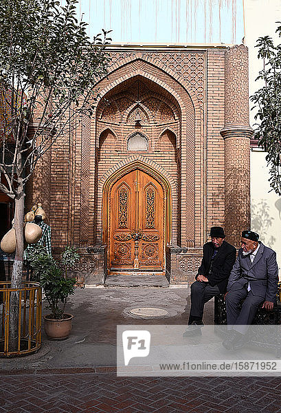 Two Uyghur Muslim men sitting outside city centre mosque  Kashgar  Xinjiang  China  Asia