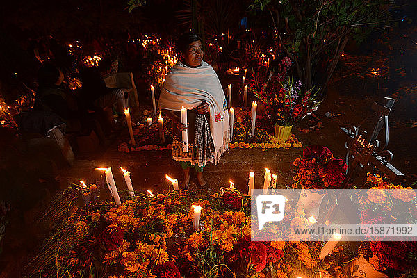 Zapotekische Frau mit Kerze zwischen mit Ringelblumen geschmückten Gräbern  Atzompa  Oaxaca  Mexiko  Nordamerika