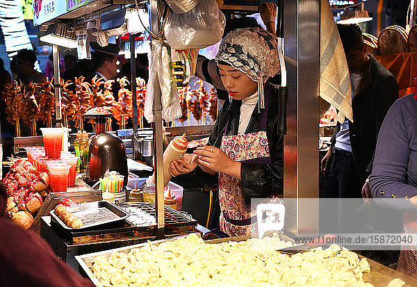 Muslimische Frau verkauft Lebensmittel an einem Stand auf dem Huajue-Nachtmarkt  Xian  Shaanxi  China  Asien