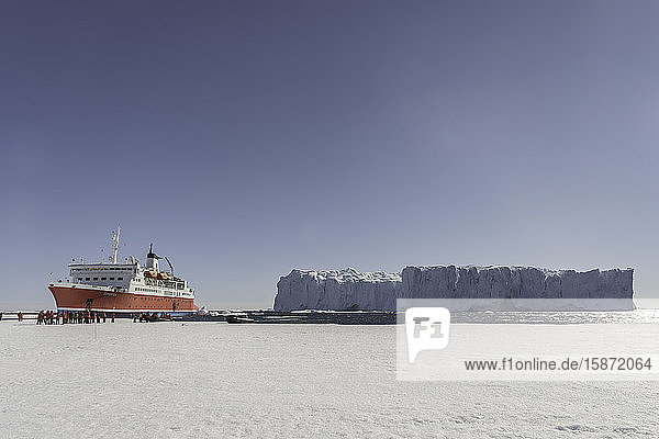 Großer Eisberg und Expeditionsschiff gegen Meereis  Antarktis  Polarregionen