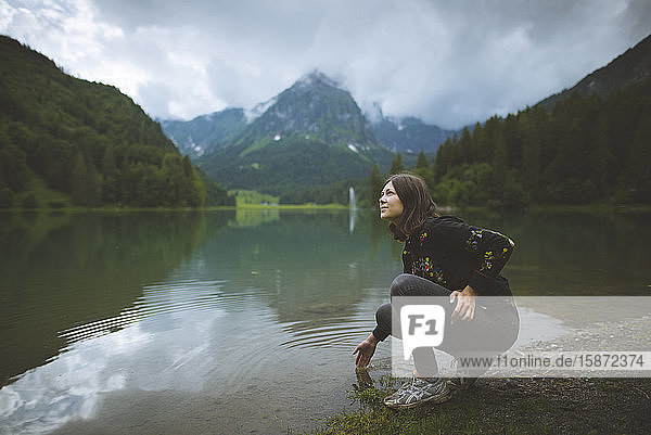 Young woman crouching by lake