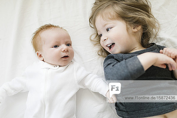 Siblings (2-5 months 2-3) lying on bed