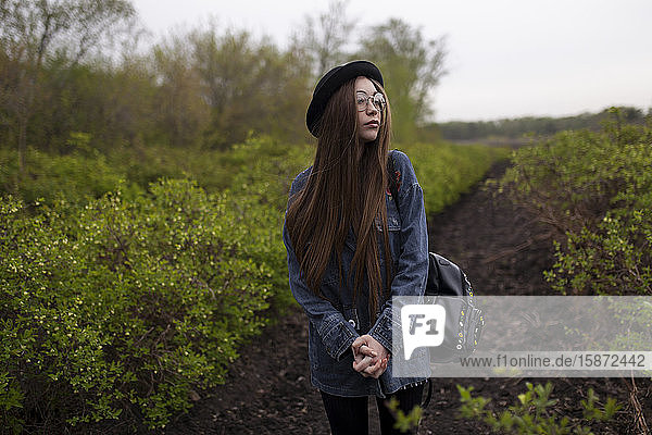 Young woman with denim jacket standing in field