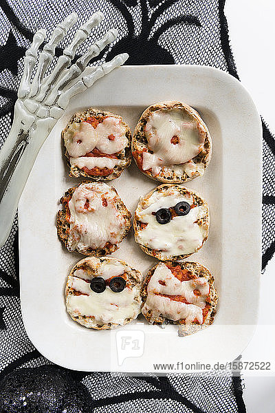 Plate of mini pizzas and hand of Halloween skeleton