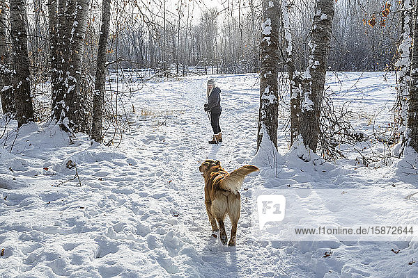 Ältere Frau geht mit Hund durch den Schnee