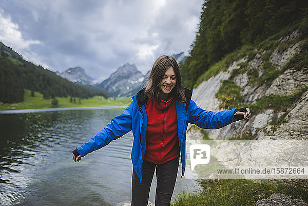 Lächelnde junge Frau in blauer Jacke am See