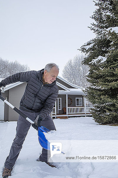 Älterer Mann beim Schneeschaufeln