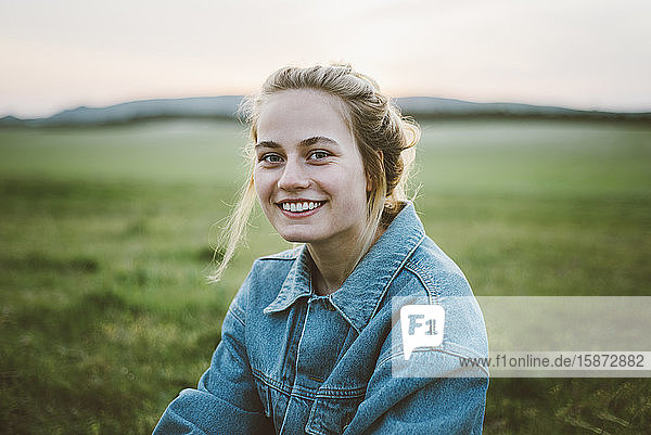 Lächelnde Frau in Jeansjacke auf einem Feld