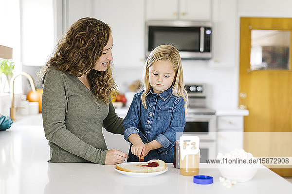 Frau macht Erdnussbutter-Gelee-Sandwich mit ihrer Tochter