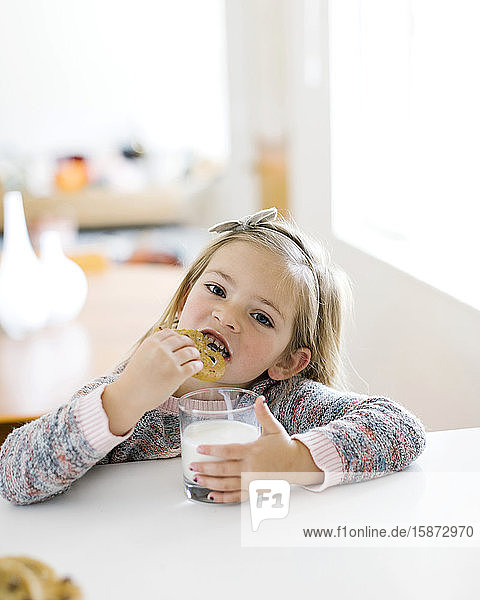 Mädchen isst Milch und Kekse
