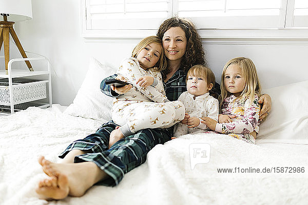 Frau sitzt mit ihren Töchtern auf dem Bett