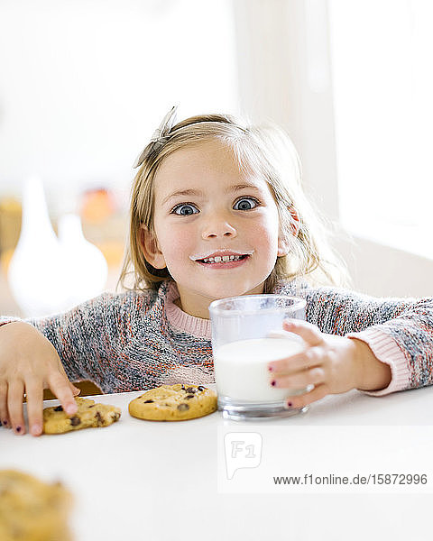 Mädchen isst Milch und Kekse