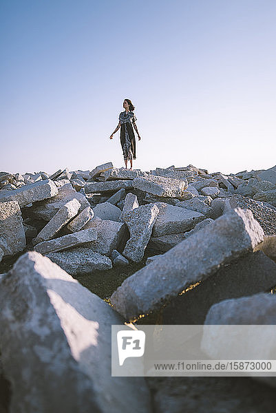 Junge Frau im Kleid auf Felsen stehend