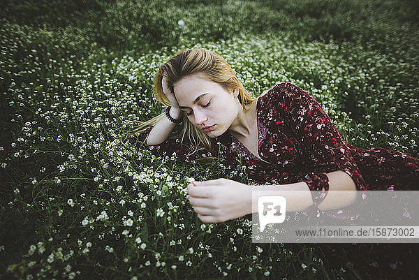 Woman wearing dress lying in meadow