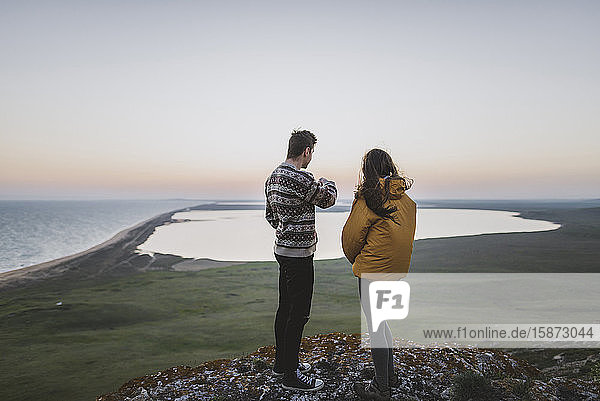 Young couple standing on hill at sunset