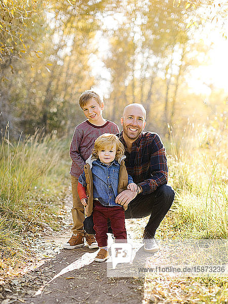 Lächelnder Mann mit seinen Söhnen auf einem Waldweg