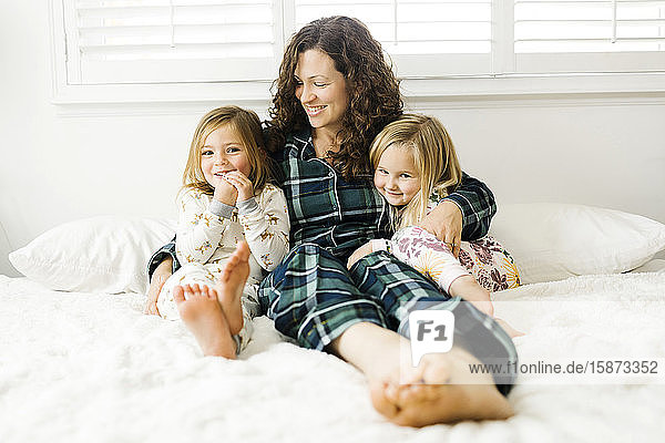 Frau sitzt mit ihren Töchtern auf dem Bett