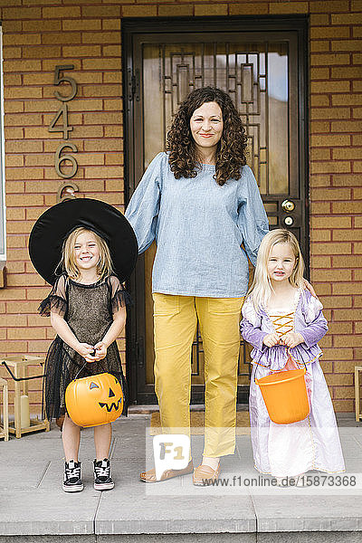 Mädchen in Halloween-Kostümen mit ihrer Mutter