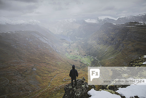 Man standing on Dalsnibba mountain overlooking valley in Geiranger  Norway