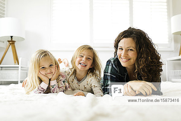 Mother and daughters lying on bed in pajamas