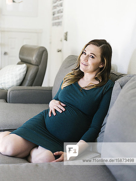 Porträt einer schwangeren Frau auf dem Sofa sitzend