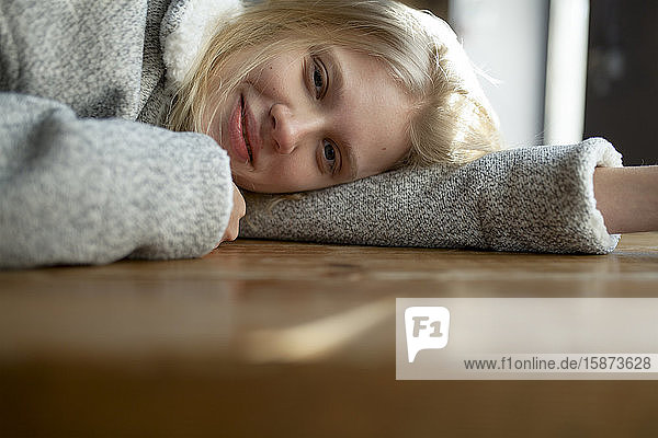 Young woman in wool coat lying on cafe table