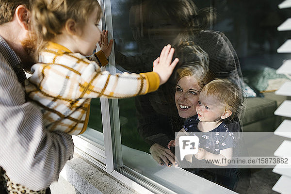 Familie mit Töchtern (2-3) auf Besuch durch das Fenster