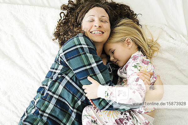 Hohe Winkelansicht von Mutter und Tochter im Pyjama auf dem Bett liegend