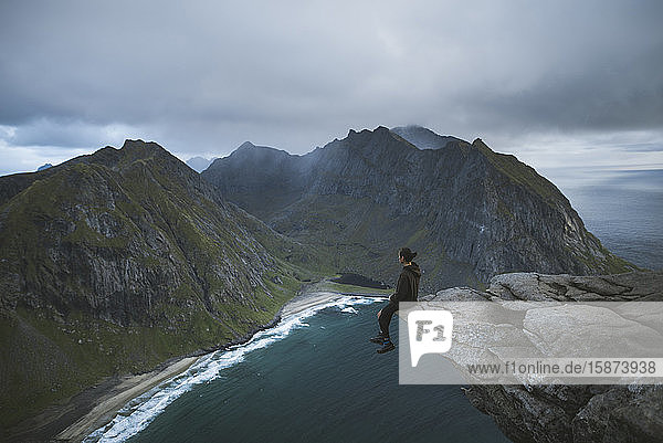 Man sitting on cliff at Ryten mountain in Lofoten Islands  Norway