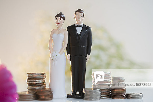Bride and Groom cake toppers next to stacks of coinsÂ 