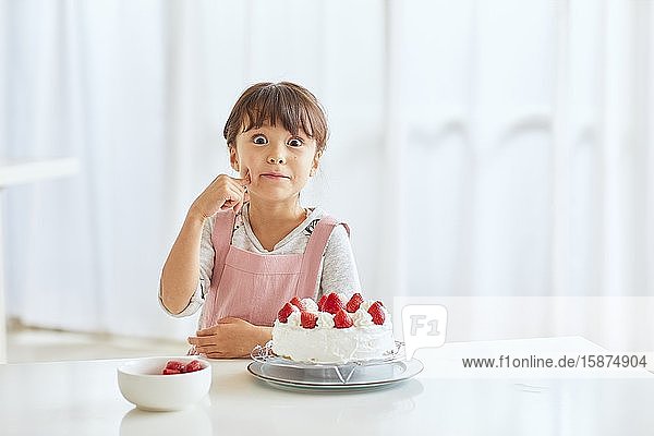 Junges glückliches Mädchen bereitet einen Kuchen in der Küche zu
