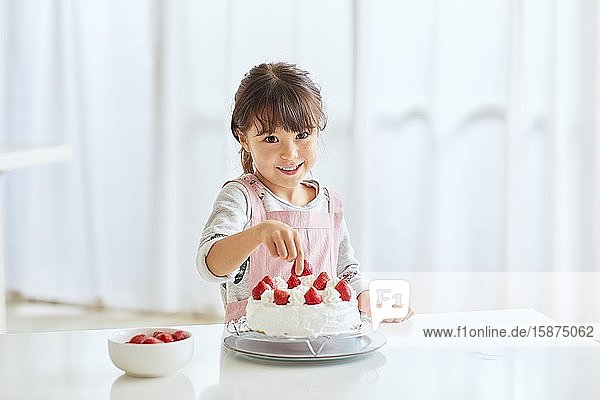 Junges glückliches Mädchen bereitet einen Kuchen in der Küche vor