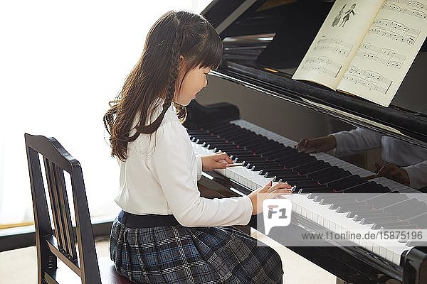 Japanisches Kind übt Klavier